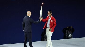 El exfutbolista del Real Madrid y de la selección francesa, ZInedine Zidane, entrega la antorcha olímpica al tenista, Rafa Nadal, durante la ceremonia de apertura de los Juegos Olímpicos de París 2024.
