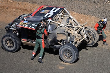 French driver Sebastien Loeb stands near his Dacia Sandrider vehicle after crashing during stage 3 of the 47th Dakar Rally between Bisha and al-Henakiyah, on January 7, 2025. (Photo by Valery HACHE / AFP)