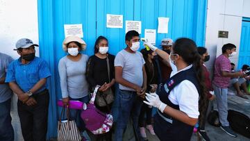 Chilean Health workers check the temperature of Peruvians queue for a safe-conduct outside their consulate in the Chilean city of Arica, on the border with Peru, on March 23, 2020 while the borders remains closed due to the coronavirus, COVID-19, pandemic. - Chile closed its land, air and sea borders on March 18. (Photo by Patricio BANDA / AFP)