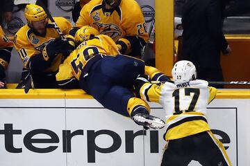 Bryan Rust, de los Pittsburgh Penguins, frena a Roman Josi, de los Nashville Predators, que le hace caer sobre sus compañeros en el banquillo.