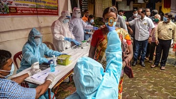 A health worker wearing a Personal Protective Equipment (PPE) suit checks the body temperature of a resident (C) during a COVID-19 coronavirus screening in Mumbai on August 12, 2020. (Photo by INDRANIL MUKHERJEE / AFP)