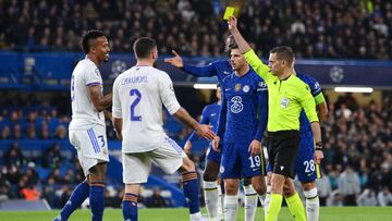 Clement Turpin muestra a Eder Militao la amarilla que acarrea sanción al brasileño para el Real Madrid-Celsea de vuelta de cuartos de final de la Champions.