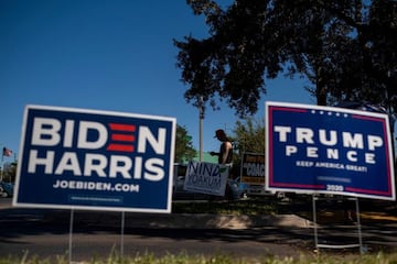 Biden and Trump campaign signs are displayed as voters line-up to cast their ballots during early voting at the Alafaya Branch Library in Orlando, Florida.