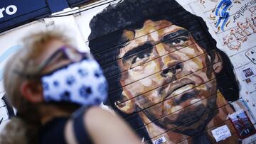 A woman stands in front of a mural of Diego Maradona outside Argentinos Juniors Club at Paternal neighbourhood in Buenos Aires, Argentina.