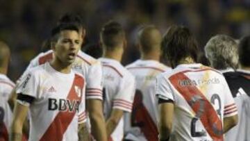 The jersey of River Plate midfielder Leonardo Ponzio (R) shows an orange strip stain presumably caused by the pepper gas he was just been sprayed with by a Boca Juniors fan, next to defender Leonel Vangioni before the start of the second half of their match against Boca Juniors at the Bombonera stadium in Buenos Aires on May 14, 2015. Boca Juniors faced the possibility of an instant exit from the Libertadores Cup Friday after their fans attacked players from arch-rivals River Plate with a pepper-spray-like substance.
 AFP PHOTO / JUAN MABROMATA