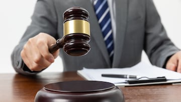 A closeup shot of a person holding a gavel on the table