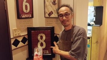 Takeuchi enseñando una camiseta dedicada de Iniesta que tiene en su restaurante.