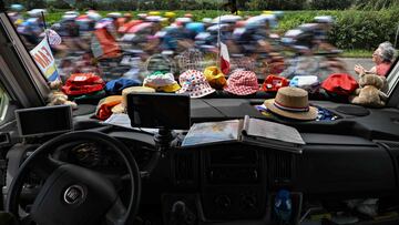 El pelotón pasa delante un coche con el sapicadero lleno de gorras y un mapa en la sexta etapa del Tour.