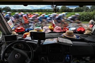 El pelotón pasa delante un coche con el sapicadero lleno de gorras y un mapa en la sexta etapa del Tour.