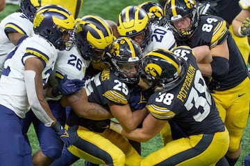 Varios jugadores de los Iowa Hawkeyes y de los Michigan Wolverines pelean por un balón durante el Big Ten Championship (Torneo de los Diez Grandes) en el Lucas Oil Stadium de Indianápolis. Michigan ganó el campeonato tras su victoria (42-3) en un partido en el que se homenajeó a las víctimas del tiroteo en el Oxford High School.