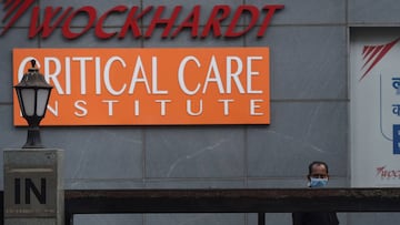 A man wearing a facemask stands on the front entrance of the Wockhardt Hospital in Mumbai on April 6, 2020. - A major private hospital in Mumbai was shut to new patients and declared a coronavirus containment zone on April 6 after 26 nurses and three doct