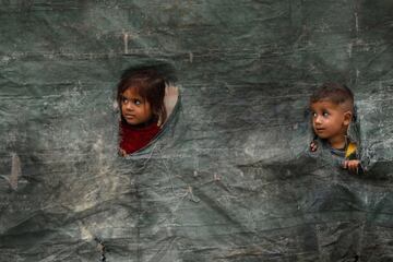 Los niños de una familia afgana miran afuera desde una tienda rota, después del aviso de Pakistán a los inmigrantes indocumentados para que se fueran, afuera de los centros de repatriación del Alto Comisionado de las Naciones Unidas para los Refugiados (ACNUR) en la ciudad de Azakhel.