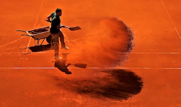 En un torneo de la categor¨ªa del Mutua Madrid Open de tenis se cuida hasta el m¨¢s m¨ªnimo detalle para que todo sea un ¨¦xito. Y mantener en buen estado el terreno de juego resulta fundamental. En la imagen, un miembro de la organizaci¨®n esparce tierra batida con una pala durante la jornada de ayer en una de las pistas exteriores de La Caja M¨¢gica.