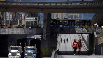 Women walk along a road near trucks as merchants block it during a protest against the Colombian government&#039;s mandatory quarantine imposed for next weekend in some main cities of the country to prevent Covid-19 contagions, in Bogota, on April 15, 2021. (Photo by Raul ARBOLEDA / AFP)