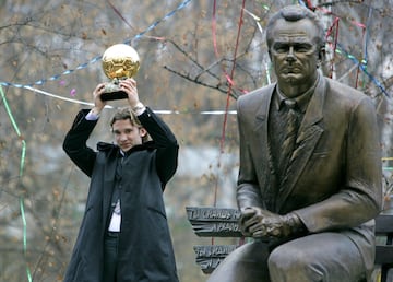 Andriy Shevchenko levanta el balón de oro junto a la estatua del legendario entrenador.