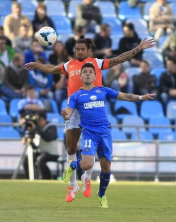 El delantero del Getafe Adrián Colunga pelea un balón con el defensa argentino del Málaga, Marcos Angeleri (detrás) en partido de la trigésima quinta jornada de liga en Primera División que se disputa esta tarde en el Coliseo Alfonso Pérez. 