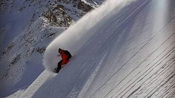 Luca Pandolfi cortando la nieve en un descenso por una montaña nevada con su snowboard o splitboard, dejando una estela de nieve a su paso.