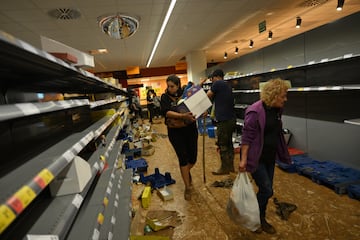 La gente recoge productos en los pasillos cubiertos de barro de un supermercado Consum que fue vandalizado después de que las inundaciones afectaran gran parte del país el 31 de octubre de 2024 en el municipio de Paiporta en Valencia, España.