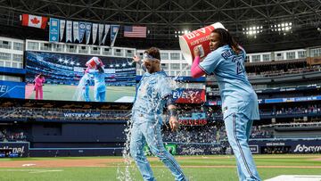 TORONTO, ON - MAY 14: Vladimir Guerrero Jr. #27 (R) of the Toronto Blue Jays gives an ice bath to teammate Danny Jansen #9 during his post-game interview after Jansen hit a walk-off two-run single to win the game against the Atlanta Braves at Rogers Centre on May 14, 2023 in Toronto, Canada.   Cole Burston/Getty Images/AFP (Photo by Cole Burston / GETTY IMAGES NORTH AMERICA / Getty Images via AFP)