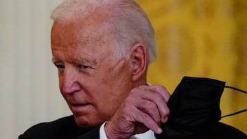 Joe Biden removes his face mask as he arrives to deliver remarks on the coronavirus disease (COVID-19) response and vaccination program in the East Room at the White House in Washington. 