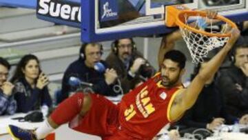 El pivot de UCAM Murcia C&eacute;sar Lima se cuelga de la canasta despu&eacute;s de un mate, durante el partido frente al Valladolid.