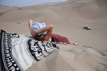 Una mujer tumbada en la arena mientras que un competidor pasa durante el Rally Dakar 2018