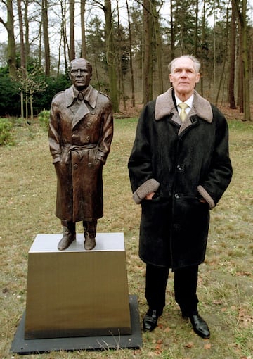 El entrenador junto a su retrato escultórico.