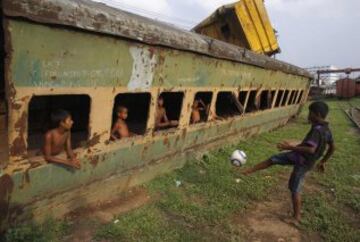 MAYO 2014. Un grupo de niños juegan al futbol en un tren abandonado en Dhaka, India. 
