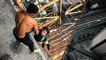 El skywalker Carlos Rengifo cogiendo de la mano a otra acr&oacute;bata que cuelga de la cornisa en lo alto de la Torre David de Caracas (Venezuela).