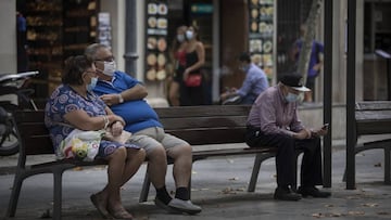 Imagen de un matrimonio sentada en un extremo de un banco, y al otro extremo, otra persona mayor; portando todos ellos una mascarilla.