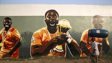 A man walks past graffiti of the Ivory Coast captain Yaya Toure with the 2015 Africa Cup of Nations trophy in Treichville district