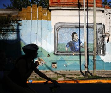 BUENOS AIRES, ARGENTINA - NOVEMBER 27: A person rides her bicycle past a mural of Diego Maradona on November 27