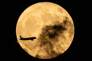 Un avión vuela frente a la luna llena, también conocida como la Luna de las Flores, sobre el norte de Londres.