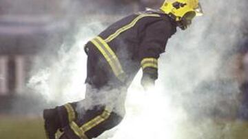 <b>INCIDENTES. </b>Un bombero retira del césped de Riazor una de las bengalas que hubo en el derbi de ida.