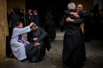 Un penitente de la hermandad de Los Estudiantes es bendecido tras confesarse con un sacerdote mientras se preparan para salir en procesión durante la Semana Santa en Sevilla.