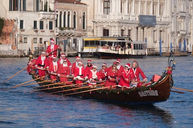 Personas vestidas de Papá Noel reman durantela  regata navideña en el Gran Canal de Venecia.