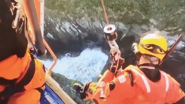 Un miembro de Salvamento Mar&iacute;timo desciende desde el helic&oacute;ptero a la zona rocosa de la playa de La Cristina (Valdovi&ntilde;o, A Coru&ntilde;a, Galicia) para rescatar a tres surfistas aislados entre las rocas. El 29 de octubre del 2020.