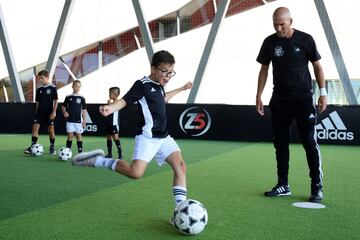 French former football player and today Real Madrid's head coach Zinedine Zidane gives a child advises to shoot the ball during the presentation of a sports and educational program called "Zidane Five Club" (ZFC), at his futsal facility, in Aix-en-Provence, southern France, on August 19, 2020. (Photo by Christophe SIMON / AFP)