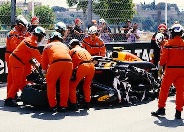 Los operarios intentan desplazar fuera de pista el monoplaza del piloto mexicano de Red Bull Racing.