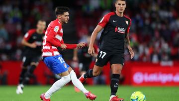 GRANADA, SPAIN - OCTOBER 03: Carlos Neva of Granada CF passes the ball whilst under pressure from Erik Lamela of Sevilla during the La Liga Santander match between Granada CF and Sevilla FC at Nuevo Estadio de Los Carmenes on October 03, 2021 in Granada,