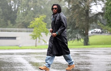 Jules Koundé, con gabardina, vaqueros y botas. 