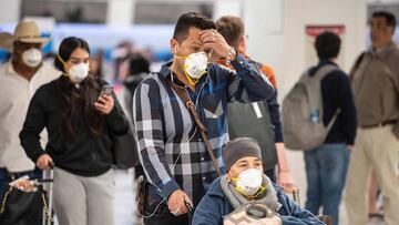 Passengers wear face masks at Benito Juarez International airport, in Mexico City, on March 21, 2020. - International flights keep operating in Mexico, unlike most other countries which have closed airports due to the outbreak of the new coronavirus, COVID-19. (Photo by PEDRO PARDO / AFP)