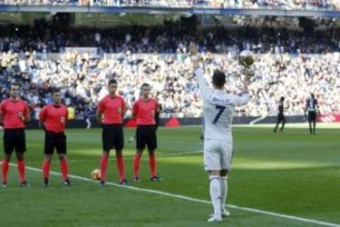 Cristiano ofrece a la grada del Santiago Bernabéu su cuarto galardón como mejor futbolista del mundo.