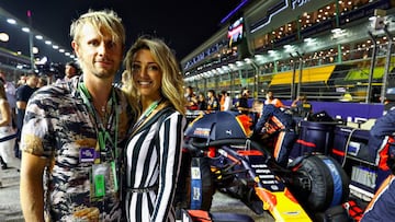 SINGAPORE, SINGAPORE - SEPTEMBER 22: Dominic Howard of the band Muse poses for a photo with Stacie Costello with the car of Max Verstappen of Netherlands and Red Bull Racing on the grid before the F1 Grand Prix of Singapore at Marina Bay Street Circuit on