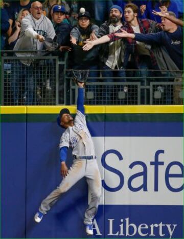 El jugador de los Kansas City Royals Harrod Dyson está preparado para coger la bola de béisbol del equipo rival, Seattle Mariners, aunque le ha salido competencia. Hasta cuatro espectadores ponen su mano para cogerla, aunque hay un quinto aficionado, el más avezado, que pone la gorra para cazarla. Esa pelota no llega al suelo, eso seguro. 