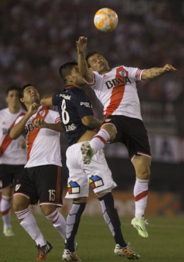 El jugador de San Lorenzo Enzo Kalinsli (c) disputa el balón con Rodrigo Mora (d) y Leonardo Pisculichi (i) de River Plate en el partido de ida de la final de la Recopa Sudamericana.