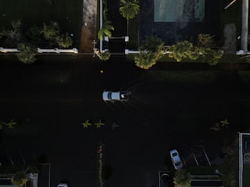 Una vista aérea de un dron muestra un automóvil circulando por una calle inundada después de que el huracán Milton tocara tierra en el sur de Daytona, Florida.