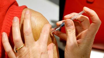 A pharmacist vaccinates a patient against the seasonnal flu at a pharmacy in Paris on october 13, 2020. (Photo by Ludovic MARIN / AFP)