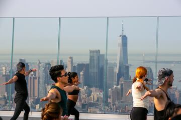 Un grupo de personas hace yoga en la azotea de un edificio de Manhattan (Nueva York). Como ocurre con muchos tipos de ejercicios al aire libre, esta práctica cogió gran demanda durante la pandemia del coronavirus, y no se ha pasado de moda, sino más bien al contrario: hay semanas de lista de espera para asistir a las clases.