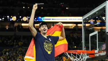 Aday Mara, pívot de Michigan Wolverines, celebra el triunfo cortando la red de la canasta, mientras luce la bandera de España.